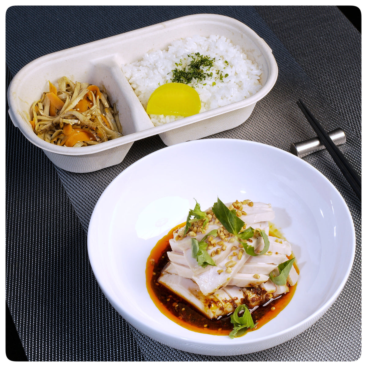 OKA-OKA Asian meal with steamed rice, pickled vegetables, and sliced chicken in spicy sauce