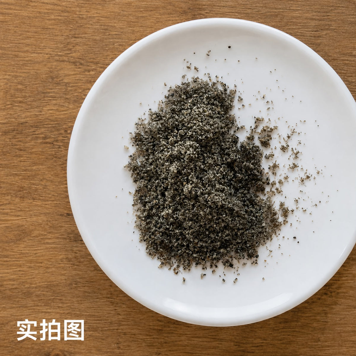 Ground black sesame seed in a white dish on a wooden surface, ideal for cooking and baking