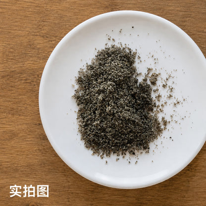 Ground black sesame seed in a white dish on a wooden surface, ideal for cooking and baking